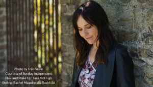 Musician Annmarie Cullen leaning against a wall and looking down